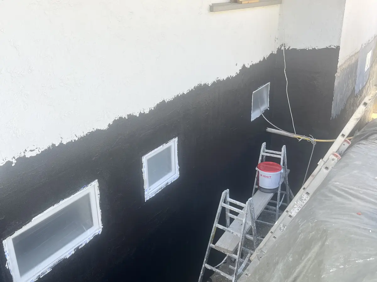 Fassade mit frisch aufgetragenem schwarzen Sockelanstrich