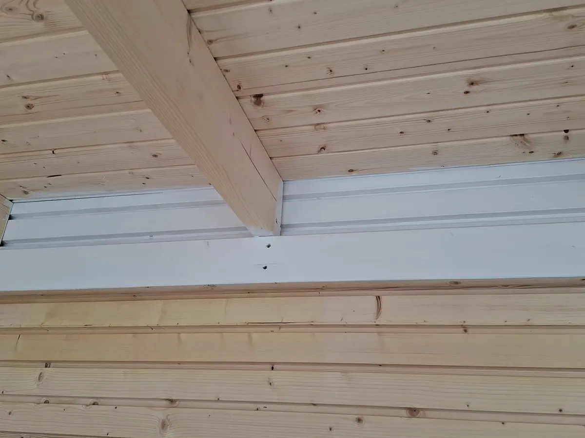 Holzdecke und -wand mit Sichtbalken und weißem Trägerprofil – Lasur- und Anstricharbeiten